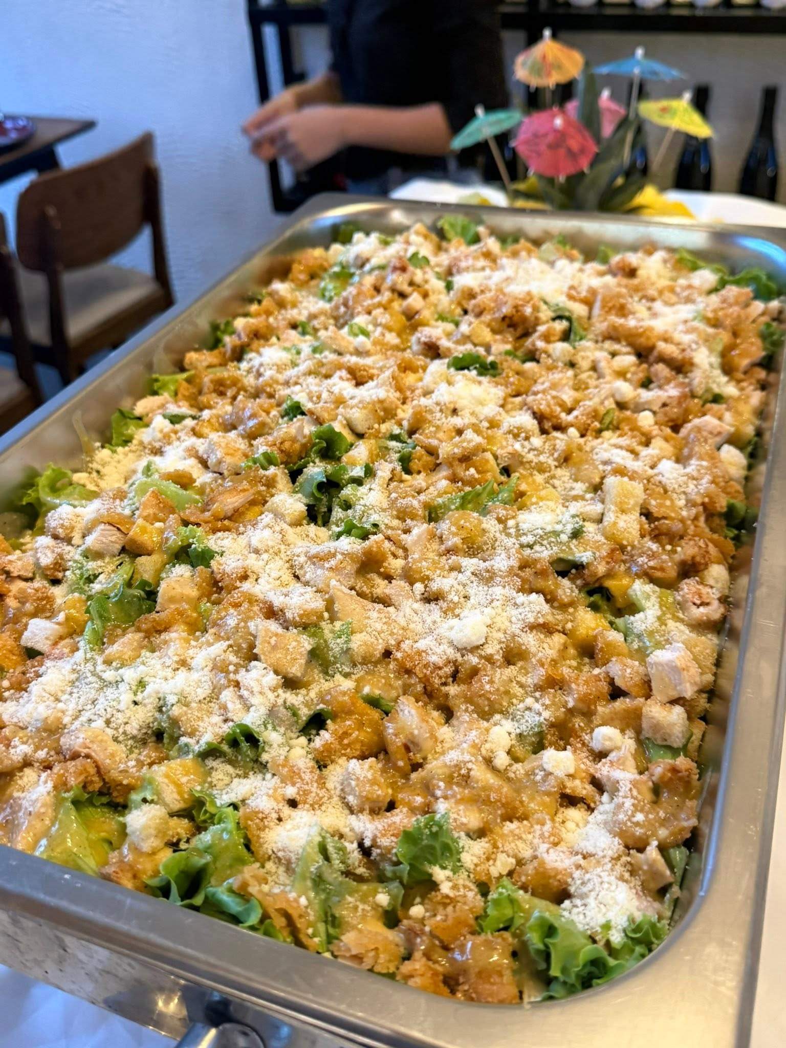 A tray of salad with croutons, chicken, greens and grated cheese
