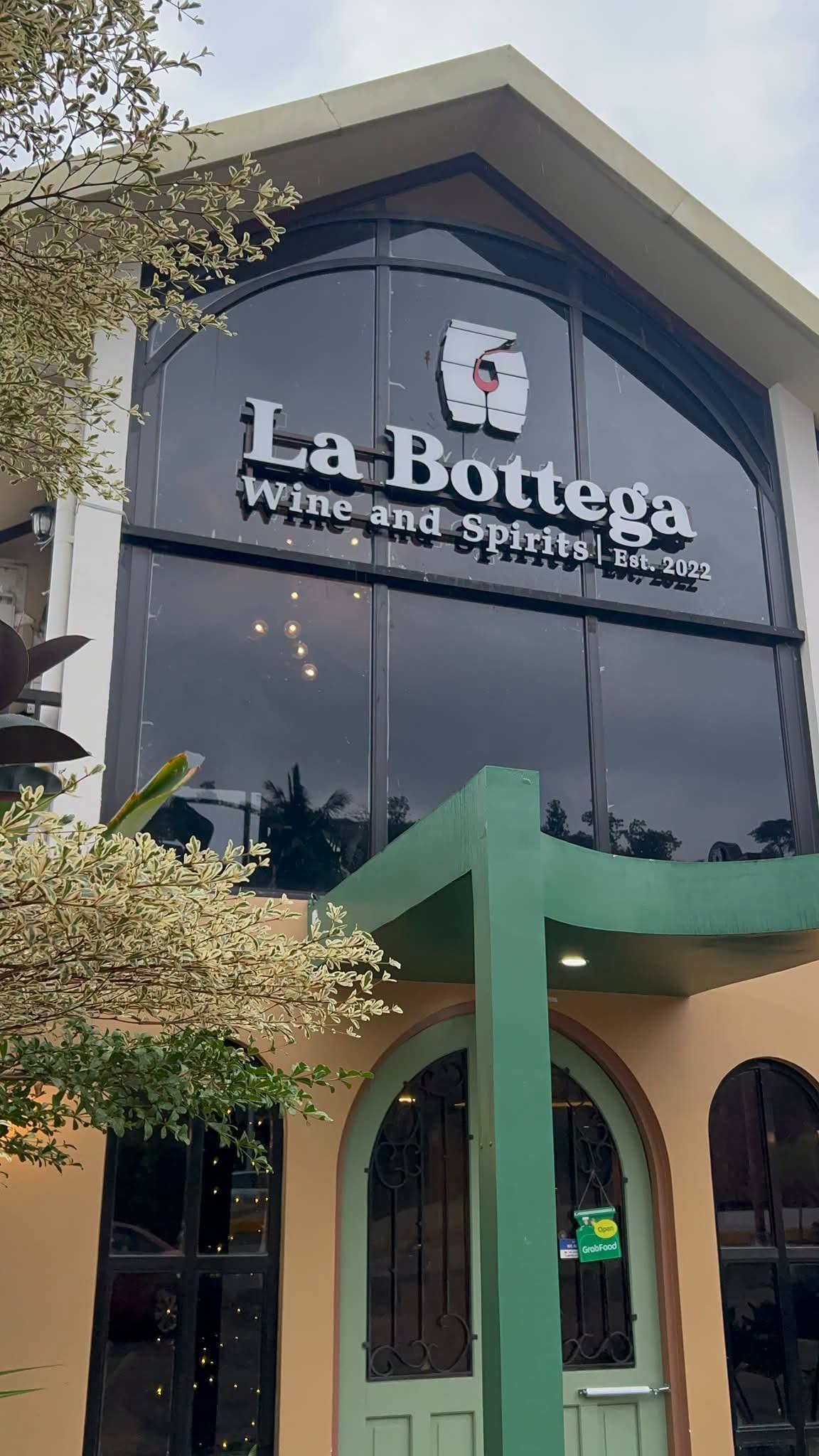 La Bottega Sambas: signage above tall arched windows and a green canopy over arched front doors