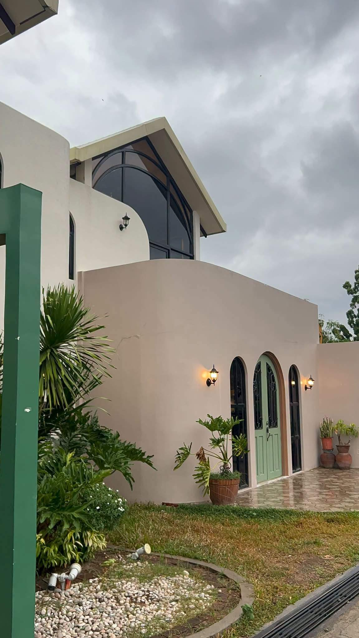 Side of the cream La Bottega building with arched doors and a lawn