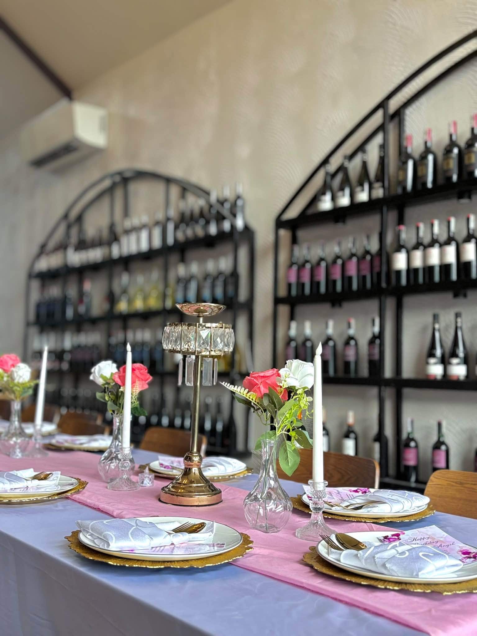 Wine shelves behind a table set with a crystal centrepiece, candles and pink roses