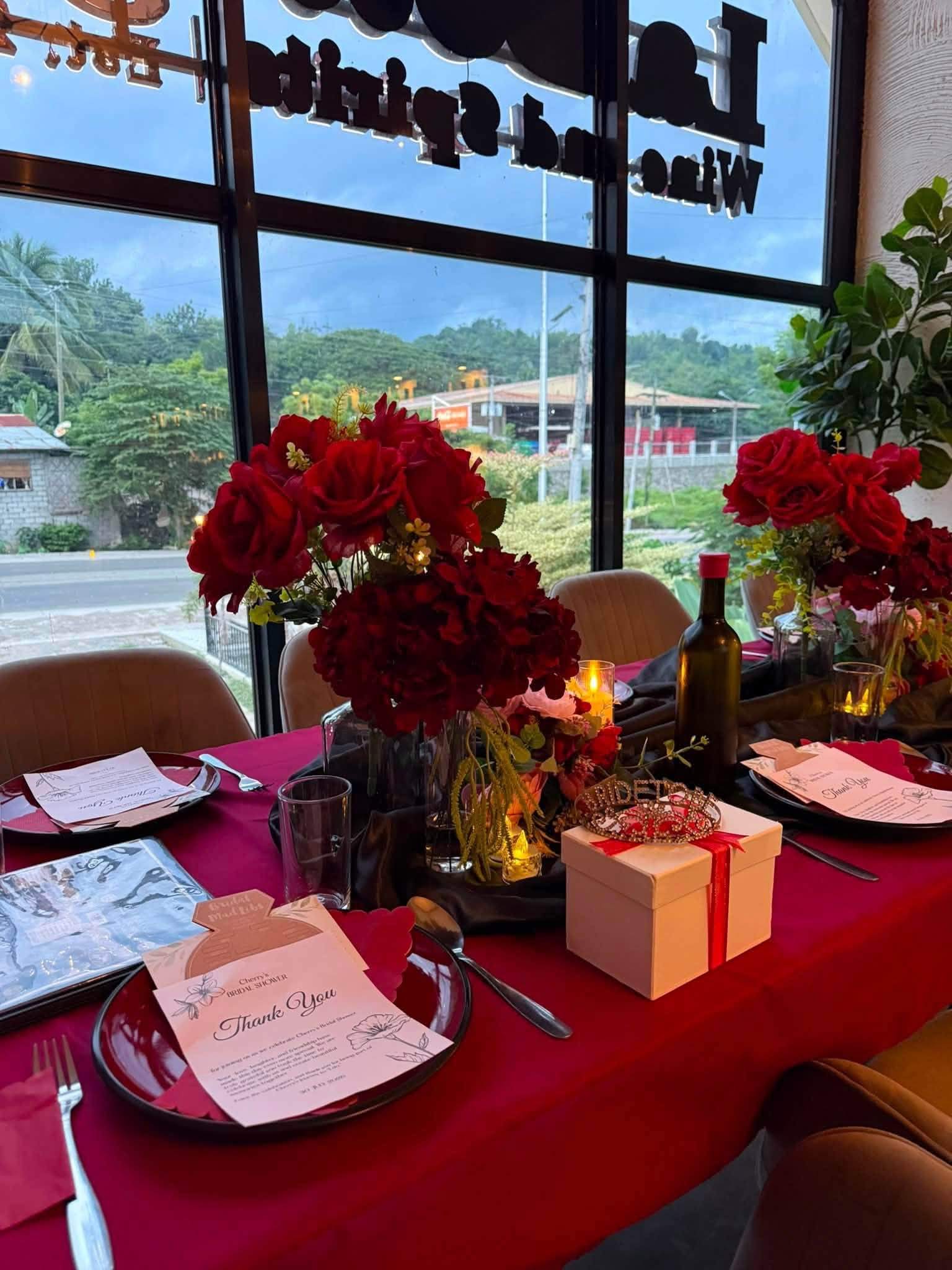 Red table linens and roses set for a celebration by the window