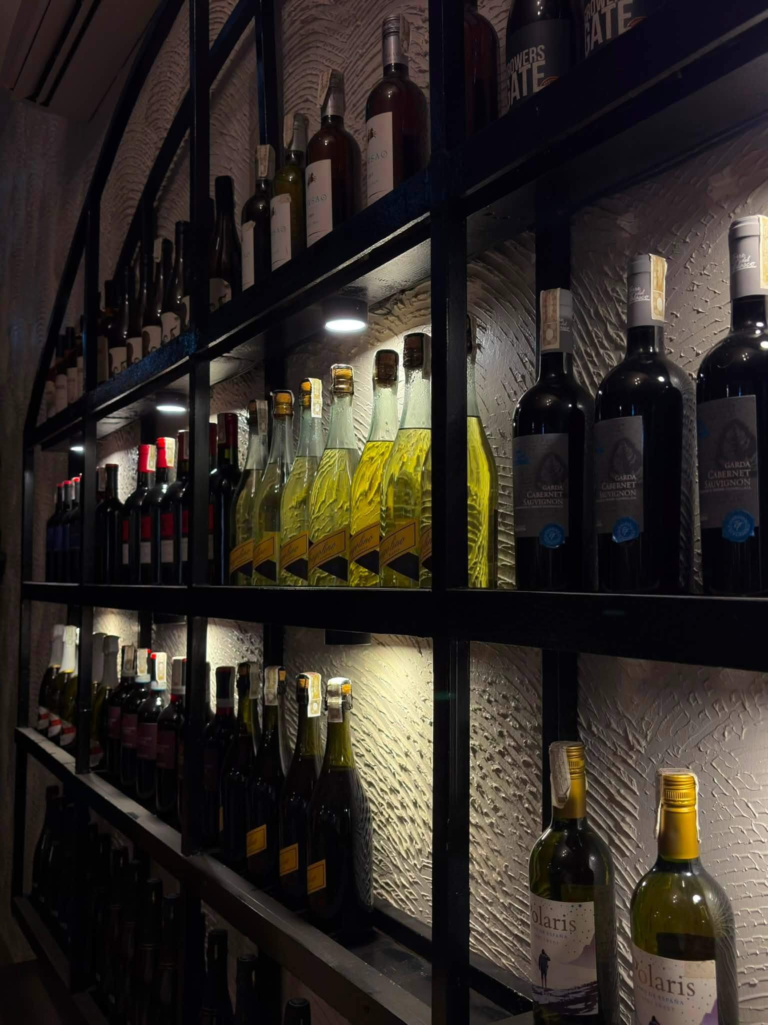 Shelves of red and white wine against a textured white wall